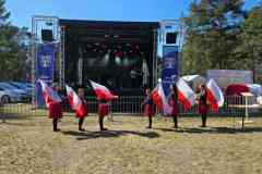 Dziewczeta-ze-Szkoly-Podstawowej-w-Jeleniu-ubrane-w-czarne-bluzki-i-czerwone-spodnice-wykonuja-uklad-choreograficzny-z-flagami