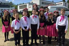 Uczniowie-SP-w-Jeleniu-pozuja-do-wspolnego-zdjecia.-Dziewczeta-w-rozowych-spodniczkach-z-wiankiem-we-wlosach-chlopcy-w-stroju-galowym-z-rozowa-wstazka-pod-szyja