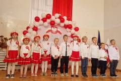 Wystep-uczniow-z-oddzialu-przedszkolnego-oraz-klasy-I.-Dzieci-spiewaja-przed-publicznoscia-ubrane-w-patriotyczne-stroje