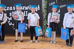 Pierwszoklasisci-pozuja-do-wspolnego-zdjecia-w-biretach-z-upominkami-w-dloniach
